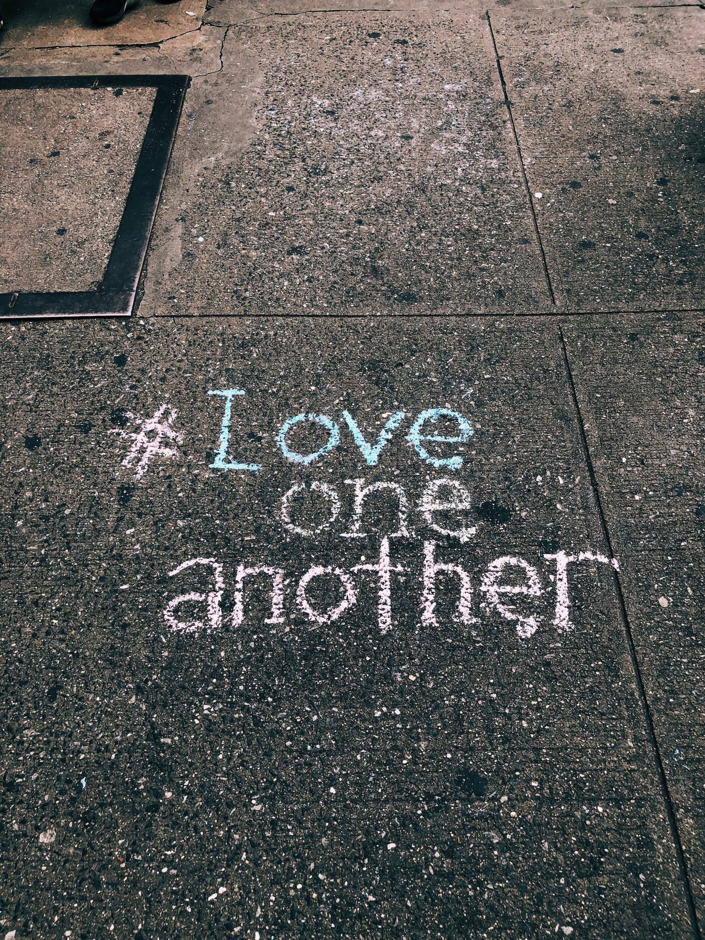 kunstiline-liebe-streetart love one another chalk written on concrete floor
